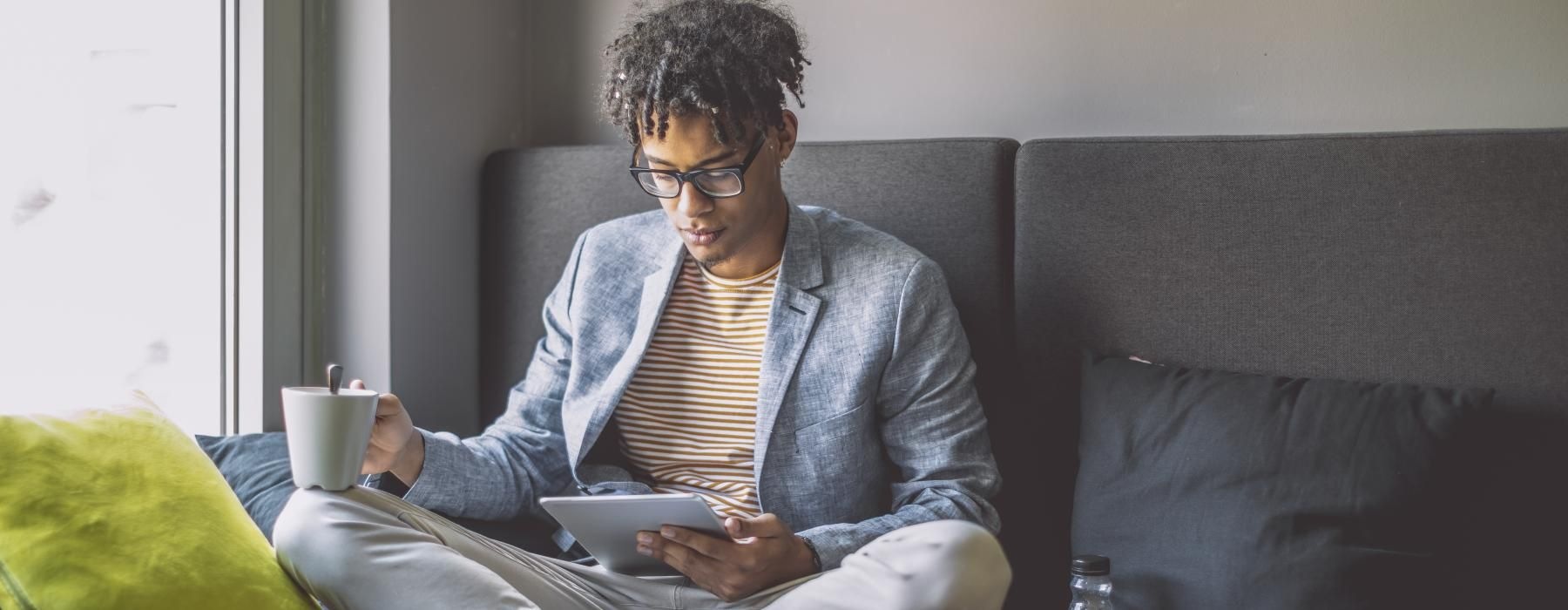 man on a couch looks at his tablet