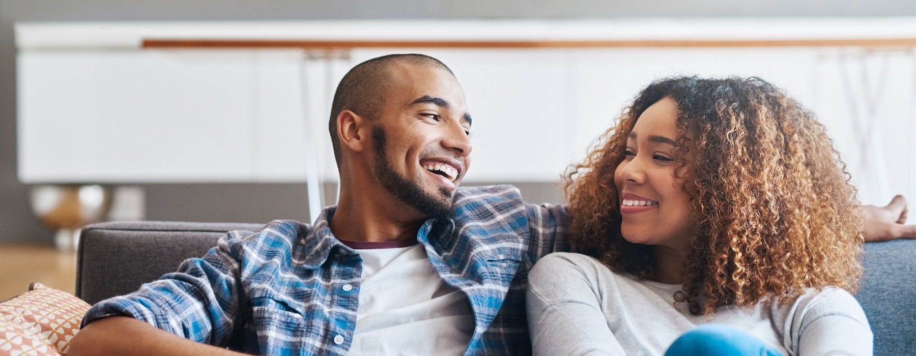 a couple sitting together on a couch smiling looking at each other