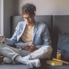 man on a couch looks at his tablet
